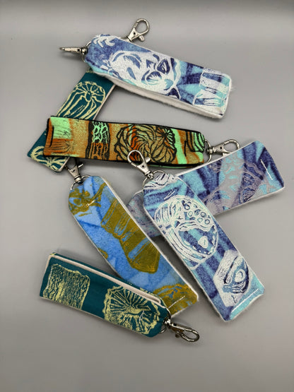 Set of fabric keychains with artistic designs on a gray background