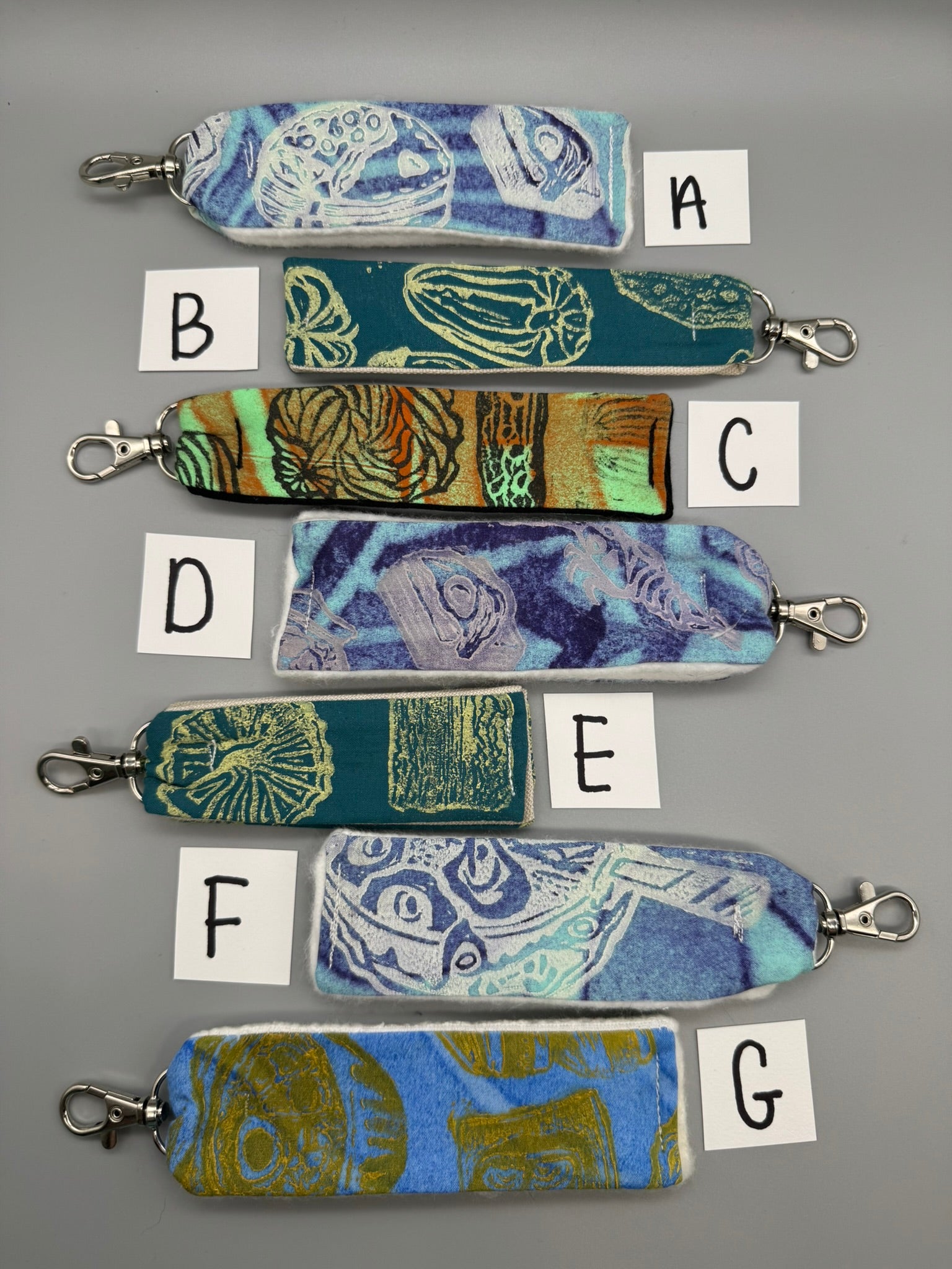 Set of colorful fabric keychains with labels on a gray background