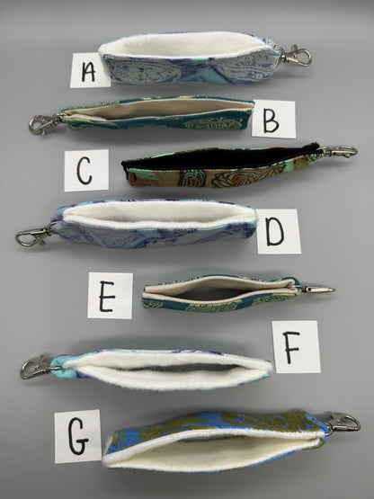 Set of fabric pouches with keychains labeled A to G on a gray background